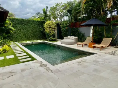 a pool in a backyard with chairs and an umbrella at Villa Iris in Dalung