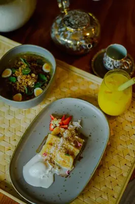 a table with a plate of food and a bowl of soup at Sumitra Luxury Villas & Resort by Pramana in Sanur