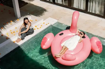 a woman laying on a pink inflatable raft in a pool at Maribel Villa Bali in Seminyak
