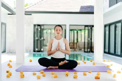 a woman sitting in a yoga pose in front of a pool at Maribel Villa Bali in Seminyak