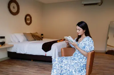 a woman sitting in a chair looking at a book at Maribel Villa Bali in Seminyak