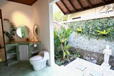 a bathroom with a toilet and a wall with plants at Villa Santai, huge garden Seminyak square in Seminyak