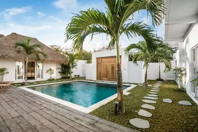 a swimming pool in front of a house with a palm tree at A Casa Di Renucci by Alfred in Bali in Seminyak