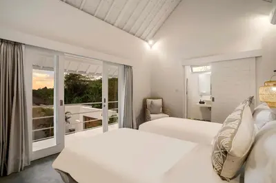 a white bedroom with two beds and a balcony at A Casa Di Renucci by Alfred in Bali in Seminyak