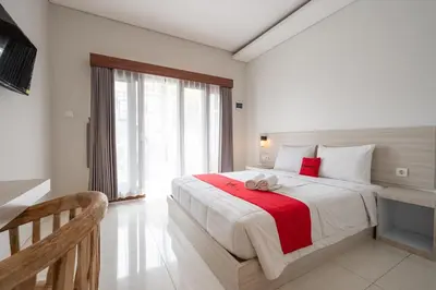 a bedroom with a large bed with a red blanket at RedDoorz Plus at Yasa's Living Denpasar in Sanur