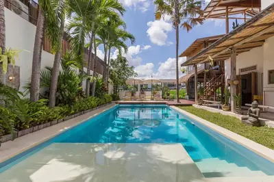 a swimming pool in the backyard of a house with palm trees at 7BR Villa Private Pool Yoga Gym Cinema 10min Canggu Surfing Beach in Kerobokan