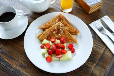 a plate of pancakes with fruit and a cup of coffee at 7 Bidadari Hotel Seminyak in Seminyak