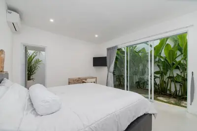 a bedroom with a white bed and a large window at Villa Vulla in Seminyak