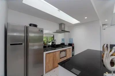 a kitchen with a stainless steel refrigerator and wooden cabinets at Villa Vulla in Seminyak