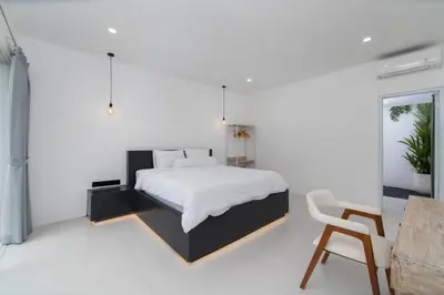 a white bedroom with a bed and a chair at Villa Vulla in Seminyak
