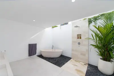 a bathroom with a bath tub and a plant at Villa Vulla in Seminyak