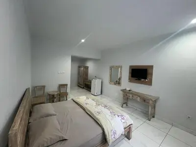 a bedroom with a large bed and a tv at Pudak Sari Homestay in Kuta