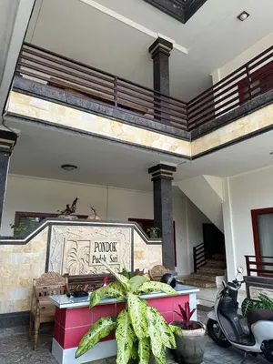 a building with a balcony and a scooter parked at Pudak Sari Homestay in Kuta