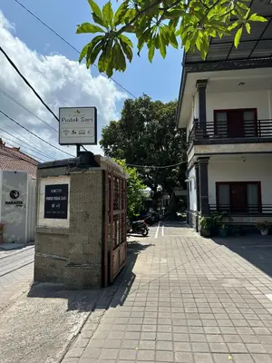 a sign for a building on the side of a street at Pudak Sari Homestay in Kuta