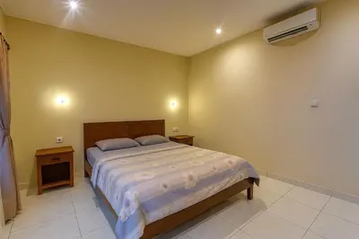 a bedroom with a large bed and a air conditioner at Pudak Sari Homestay in Kuta