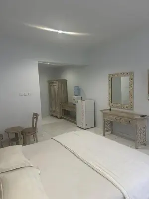 a white room with a bed and tables and a mirror at Pudak Sari Homestay in Kuta