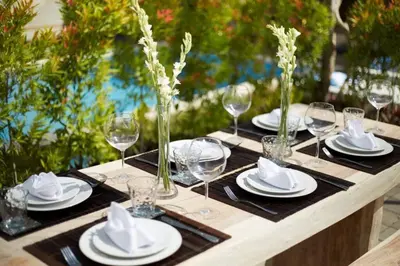 a wooden table with plates and glasses and napkins at Sol Bella VIlla 1 in Seminyak