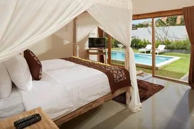 a bedroom with a canopy bed and a swimming pool at Sol Bella VIlla 1 in Seminyak