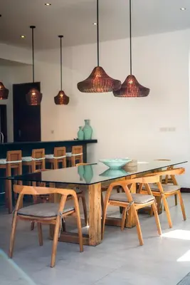 a dining room with a table and chairs and pendant lights at Villa Cuatro : Amazing 3BR Villa in Seminyak - Perfect Location in Seminyak