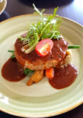 a plate of food with meat with sauce and vegetables at Mokko Suites Batubelig in Canggu