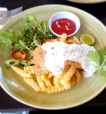 a plate of food with waffle fries and sauce at Mokko Suites Batubelig in Canggu