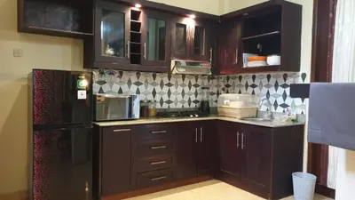 a kitchen with wooden cabinets and a black refrigerator at Moara Guest House in Kerobokan