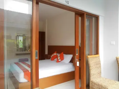 a bedroom with a bed and a sliding glass door at Tama Seminyak Town House in Kerobokan