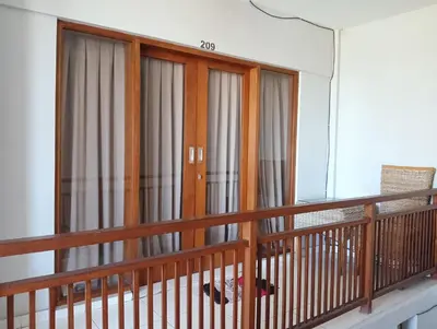 a balcony with three doors with curtains on it at Tama Seminyak Town House in Kerobokan