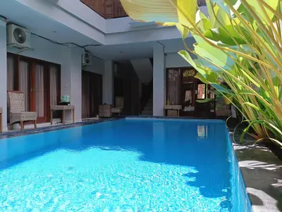 a large blue swimming pool next to a house at Tama Seminyak Town House in Kerobokan