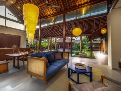 a living room with a blue couch and a table at Bumbak Park Villas By Nakula in Canggu