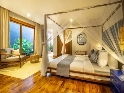 a bedroom with a canopy bed and a couch at Bumbak Park Villas By Nakula in Canggu