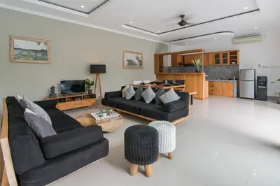 a living room with two black couches and a kitchen at Modern villa near Atlas beach club & beach in Canggu