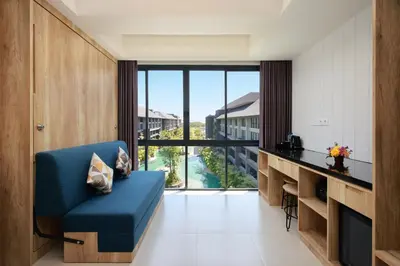 a living room with a blue couch and a large window at Anagata Hotels and Resorts Tanjung Benoa in Nusa Dua