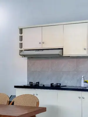 a kitchen with white cabinets and a wooden table at Apple Suite in Kerobokan