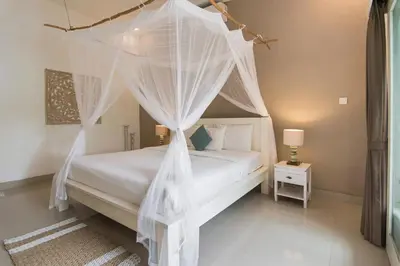 a bedroom with a white bed with mosquito netting at Incredible villa near Atlas beach club Berawa in Canggu