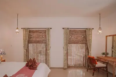 a bedroom with two windows and a bed and a desk at Bohemian Kasya Villa Bali in Seminyak