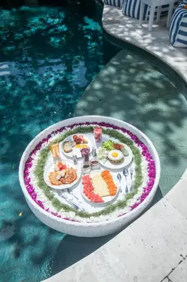a plate of food on a table next to a pool at Monroe 3BR Luxury Villa Seminyak BREAKFAST INCL Netflix Private Pool 900m to Beach in Seminyak