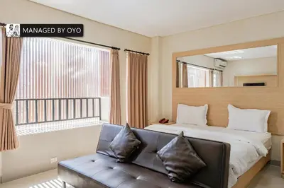a bedroom with a bed and a couch and a window at Collection O Kuta Near Airport Ngurah Rai in Kuta