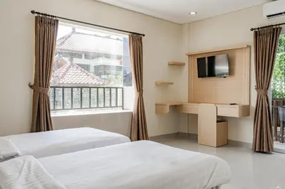a hotel room with two beds and a television at Collection O Kuta Near Airport Ngurah Rai in Kuta