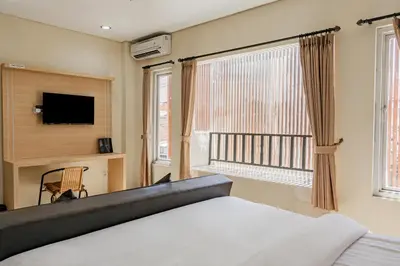 a bedroom with a bed and a tv and a window at Collection O Kuta Near Airport Ngurah Rai in Kuta