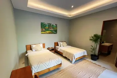 a bedroom with two beds and a painting on the wall at Modern spacious private pool villa in Central Canggu in Canggu