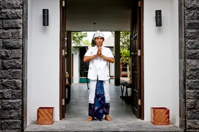 a woman standing in the doorway of a building praying at Villa Ziba in Seminyak