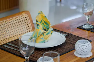 a wooden table with a plate and glasses on it at Villa Rama Sita - 100m from Eat Street, 3BR in Seminyak
