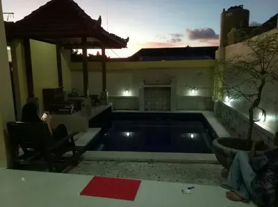a swimming pool in a house with a sunset in the background at Tambak Sari Villa in Jimbaran