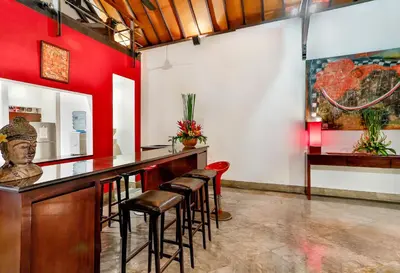a bar with stools in a room with red walls at Villa Taksu Legian in Legian