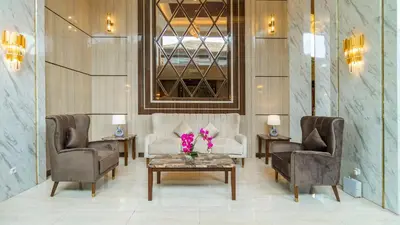 a lobby with two chairs and a table with flowers on it at City of Aventus Hotel - Denpasar in Denpasar