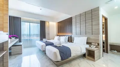 a bedroom with two beds and a large window at City of Aventus Hotel - Denpasar in Denpasar