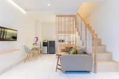 a living room with a couch and a staircase at Ellavie Aparthouse Kerobokan in Kerobokan