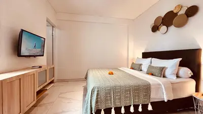 a bedroom with a bed and a tv on a wall at Ellavie Aparthouse Kerobokan in Kerobokan