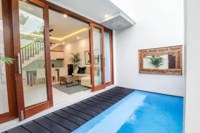 an indoor swimming pool in a house with a living room at Vienna Villas by Great Bali Villas in Seminyak